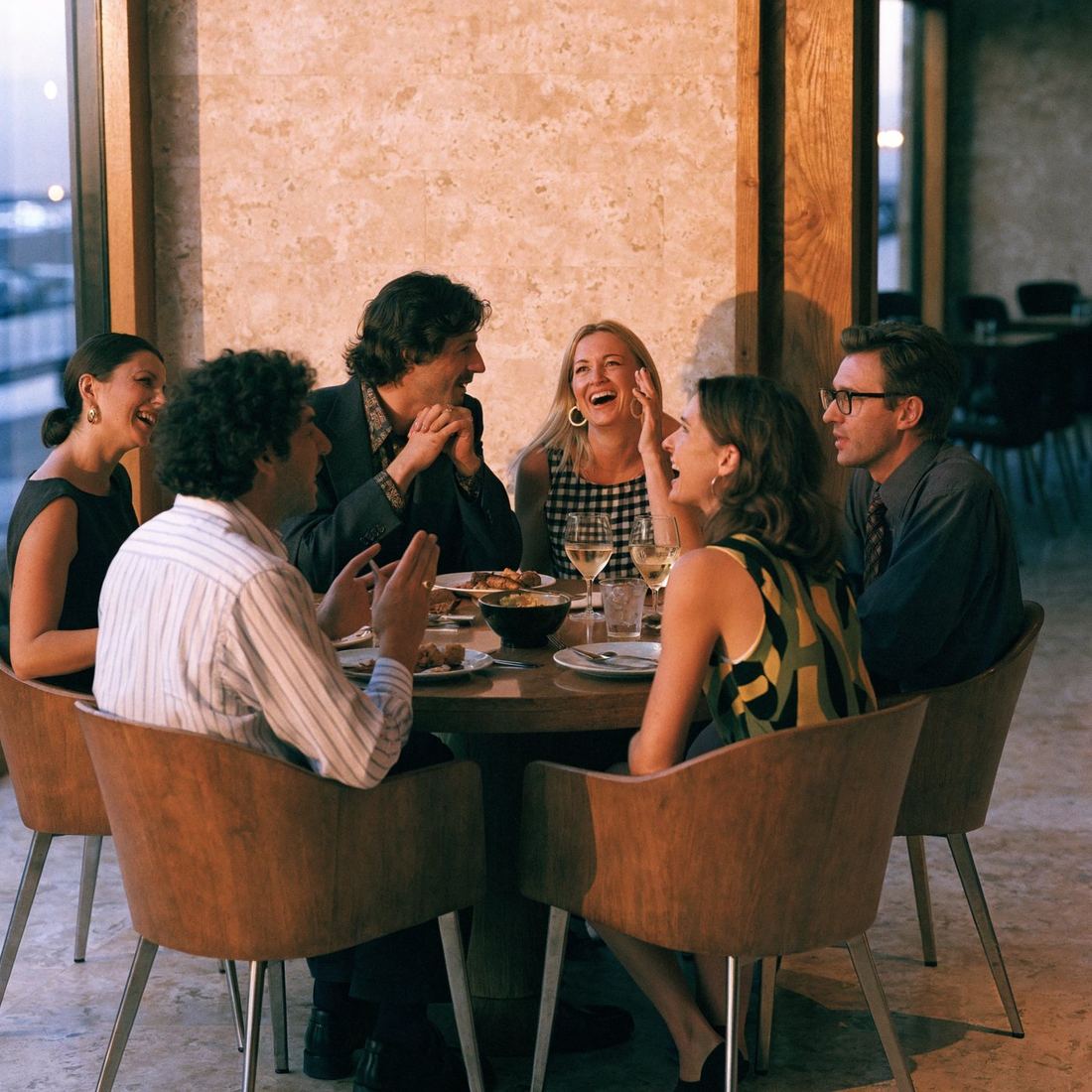 Six guests talking around a round dinner table